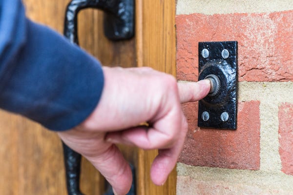 Hand pressing doorbell