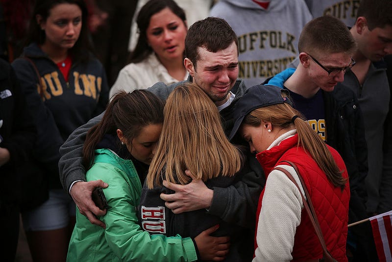 People hug and cry during a vigil for victims of the Boston Marathon bombings at Boston Commons on April 16, 2013 in Boston, Massachusetts. The twin bombings, which occurred near the marathon finish line, resulted in the deaths of three people while hospitalizing at least 140. The bombings at the 116-year-old Boston race, resulted in heightened security across the nation with cancellations of many professional sporting events as authorities search for a motive to the violence. (Photo by Spencer Platt/Getty Images)