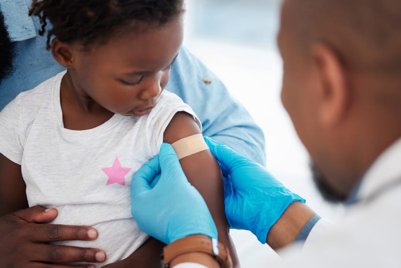 Doctor puts bandage on child after giving vaccine