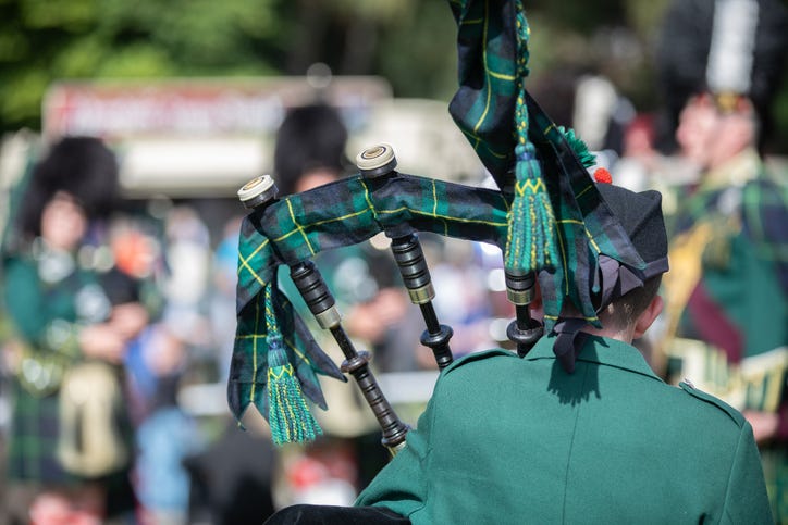 Scottish festival with the back of a bag piper playing with a larger band 
