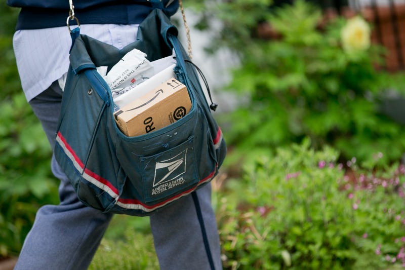 A USPS employee carries mail