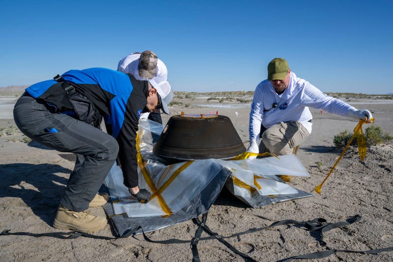 In this handout provided by NASA, from left to right, Lockheed Martin Mission Operations Assurance Lead Graham Miller, Lockheed Martin Recovery Specialist Michael Kaye, and Lockheed Martin Recovery Specialist Levi Hanish prepare the sample return capsule from NASA's OSIRIS-REx mission for transport shortly after the capsule landed at the Department of Defense's Utah Test and Training Range, on September 24, 2023 at the Department of Defense's Utah Test and Training Range in Dugway, Utah. 