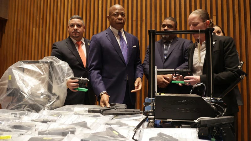 Mayor Eric Adams, middle, flanked by NYPD Commissioner Edward Caban, left, Manhattan DA Alvin Bragg and prosecutors, looks at ghost guns and printers during a news conference at NYPD Headquarters on Wednesday, Sept. 27, 2023, in New York