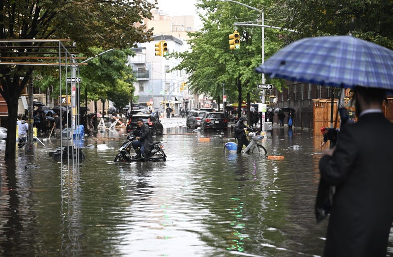 A man tries to pass a flooded street with his bicycle after a heavy rain in Williamsburg, Brooklyn, on September 29, 2023