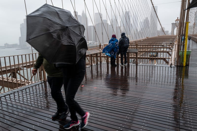 People walk over the Brooklyn Bridge during heavy rain and high winds as the remnants of Tropical Storm Ophelia continue to move through the area on September 25, 2023 in New York City
