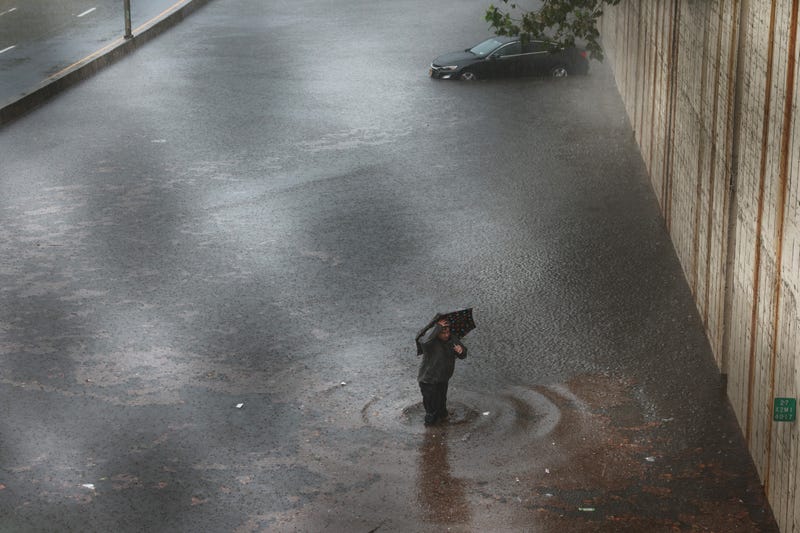 A person walks away from his vehicle after it got stuck in high water on the Prospect Expressway during heavy rain and flooding on September 29, 2023 in New York City