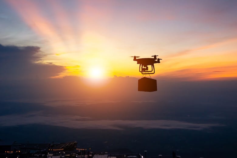 Drone delivering a package against a sunset