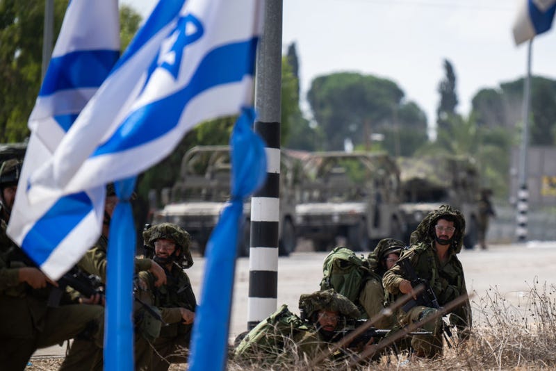 IDF soldiers guard near a waving Israeli flag outside Kibbutz Kfar Aza where dozens of civilians were killed days earlier 