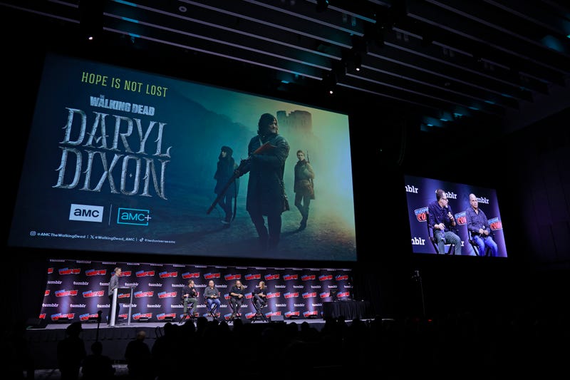 several people onstage underneath an ad for daryl dixon