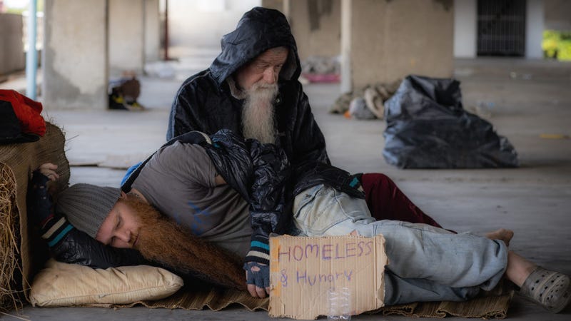 Homeless and hungry man sleeping on street with signboard