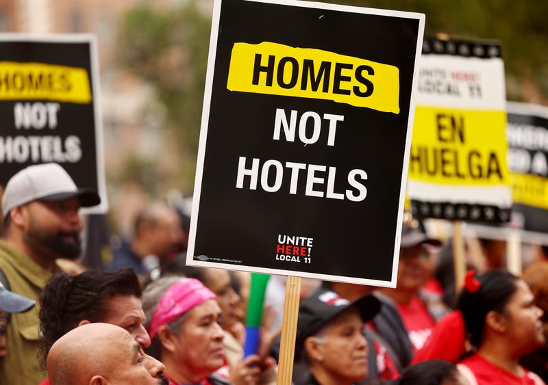 picketing worker holding sign that says homes not hotels