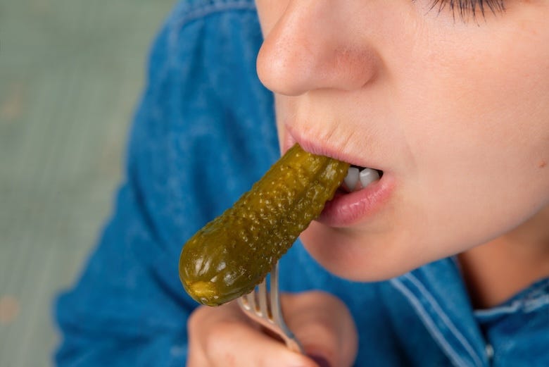 Woman biting into a pickle