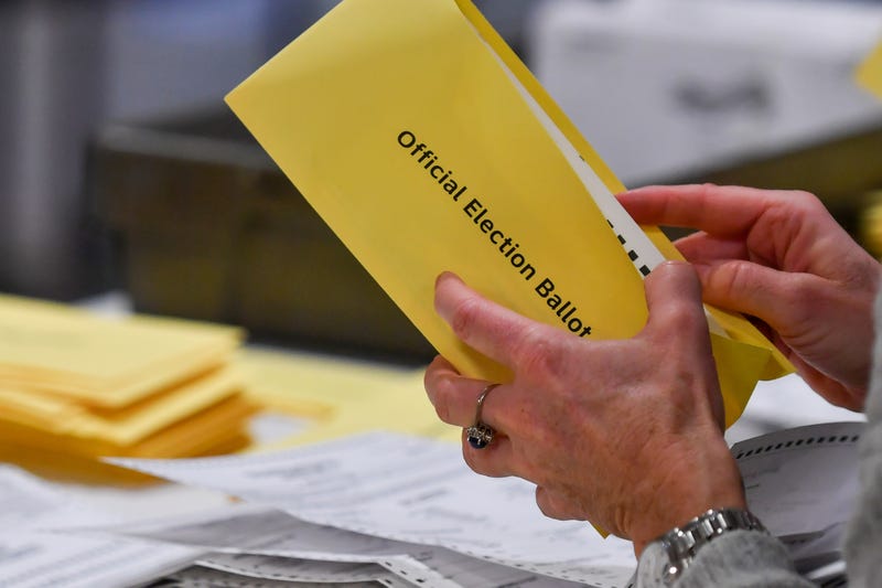 A woman takes a mail-in ballot from an envelope at a polling station in Pennsylvania.