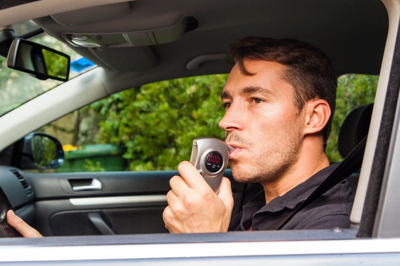 Man using breathalyzer in car