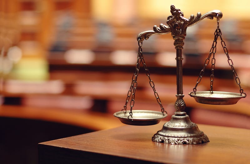 Symbol of law and justice sits in an empty courtroom.