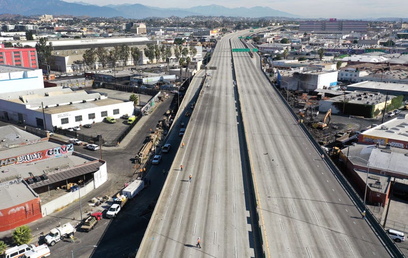 An aerial view of workers walking on the closed I-10 freeway following a large pallet fire, which occurred Saturday at a storage yard beneath the freeway (CENTER R), on November 13, 2023 in Los Angeles, California. Engineers have been assessing the extent of the damage and it remains unknown how long the freeway, which is a major commuter artery through the downtown area, will remain closed and complicate traffic for the city. California Gov. Gavin Newsom said that over 300,000 vehicles drive through the freeway corridor each day and drivers are being urged to use public transit. (Photo by Mario Tama/Getty Images)