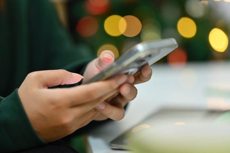 woman typing on smartphone on background of Christmas tree with lights