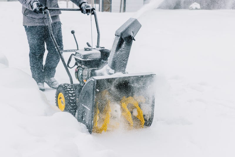 Man removes snow with a snow blower on a winter day.