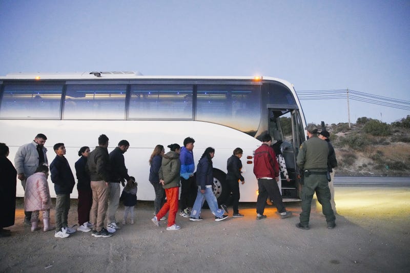 Migrants board a CBP transport bus, after crossing from Mexico on Dec. 13, 2023, in Jacumba Hot Springs, California