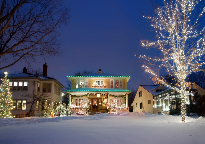 Christmas lights on a house and tree with snow in the yard