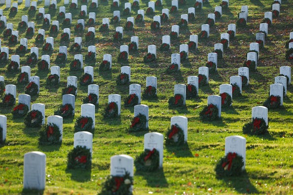 Christmas wreaths sit on a headstone during Wreaths Across America Day at the Arlington National Cemetery