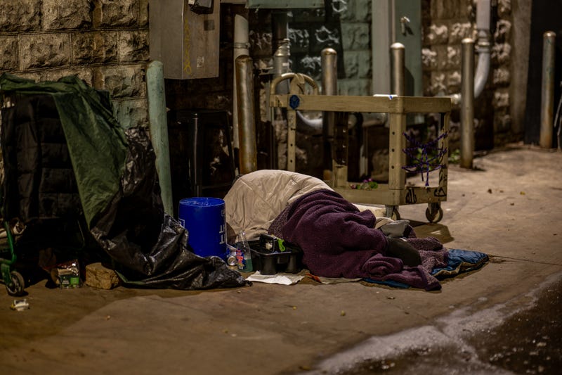 An unhoused resident sleeps in an alleyway near his cleaning supplies on Dec. 18, 2023, in Austin, Texas.