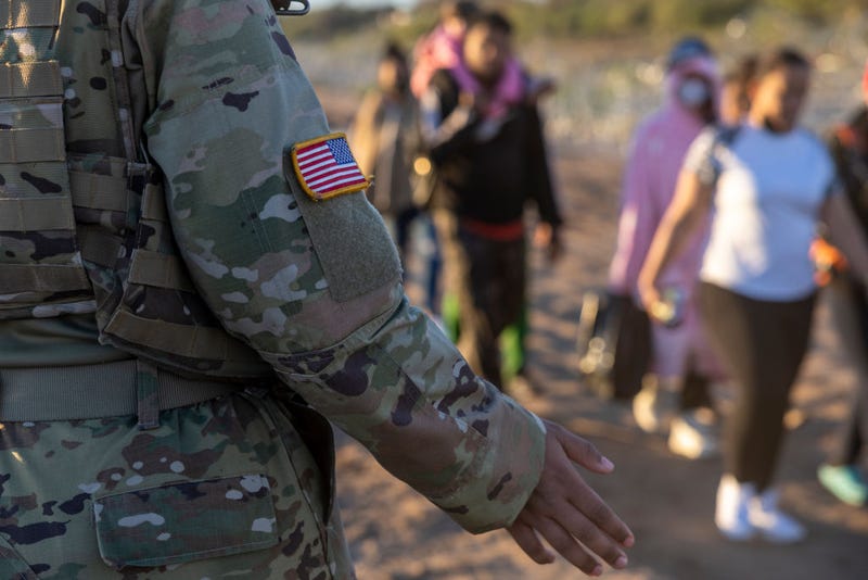A Texas National Guard soldier observes as thousands of immigrants walk towards a U.S. Border Patrol transit center on December 19, 2023 in Eagle Pass, Texas. 