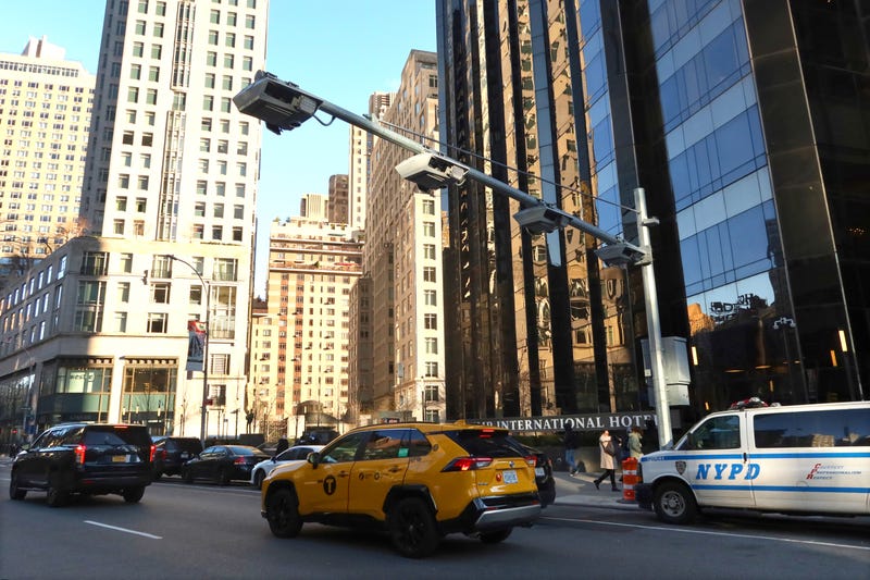 A taxi cab passes under congestion pricing toll readers hanging above Broadway in Columbus Circle on Dec. 20, 2023