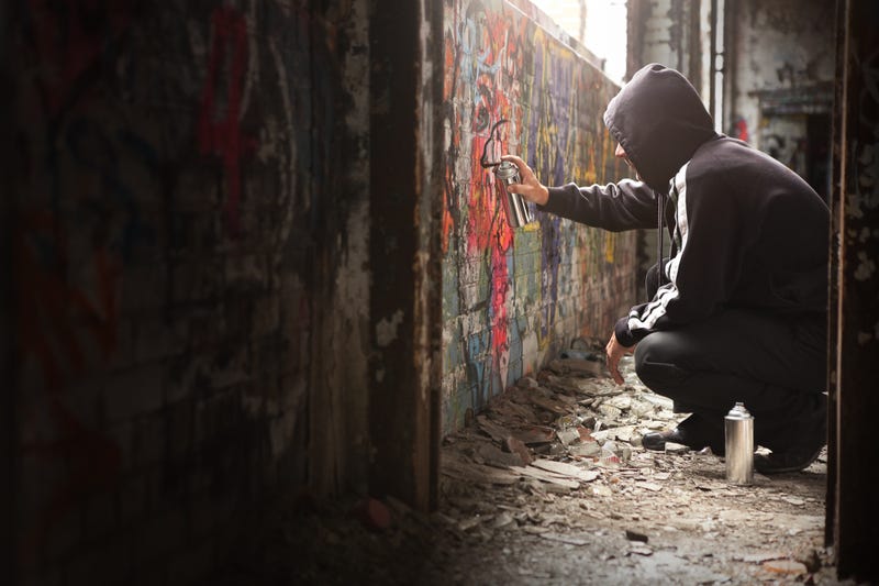 Young kid spray painting a wall.