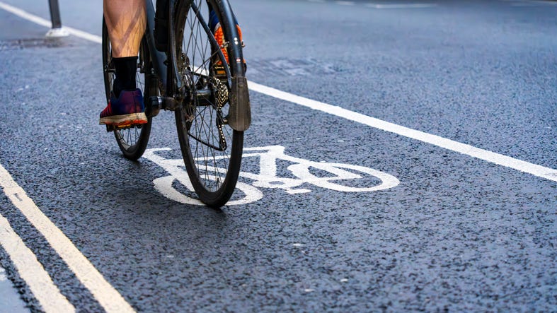 Two wheels on a bicycle are visible as a rider stays in the middle of a bike lane