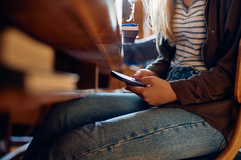 Close-up of student using a cell phone in class