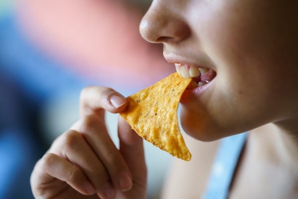 Teen biting a tortilla chip
