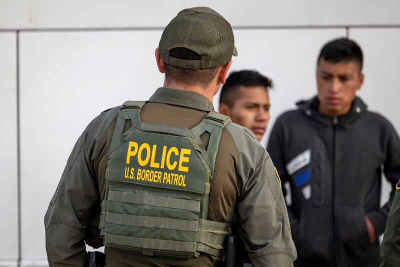 A U.S. Border Patrol agent watches as immigrants prepare to board a bus after crossing the U.S.-Mexico border on January 07, 2024 in Eagle Pass, Texas. 