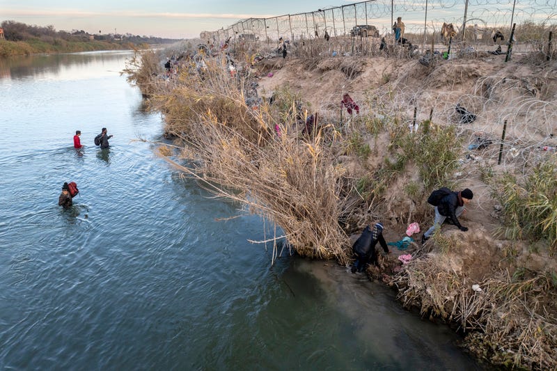 In an aerial view, immigrants climb up the bank of the Rio Grande while crossing from Mexico into the United States on Jan. 7, 2024, in Eagle Pass, Texas.