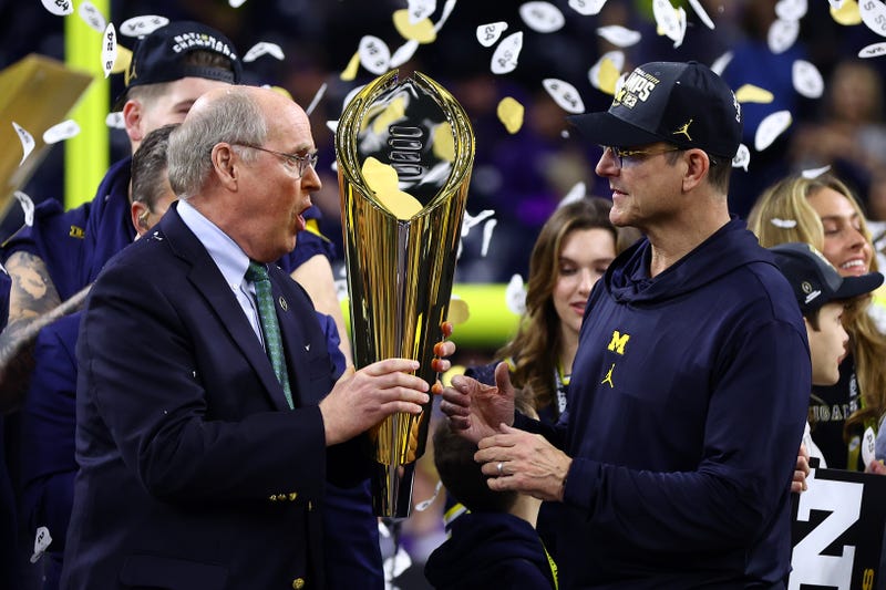 Head coach Jim Harbaugh of the Michigan Wolverines receives the national championship trophy after defeating the Washington Huskies during the 2024 CFP National Championship game at NRG Stadium