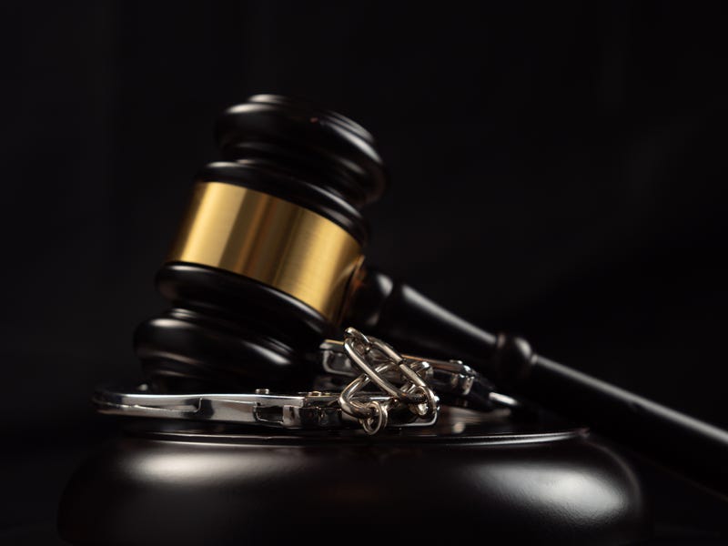 Judge's gavel and handcuffs on a dark background. Judge's gavel and handcuffs close-up.