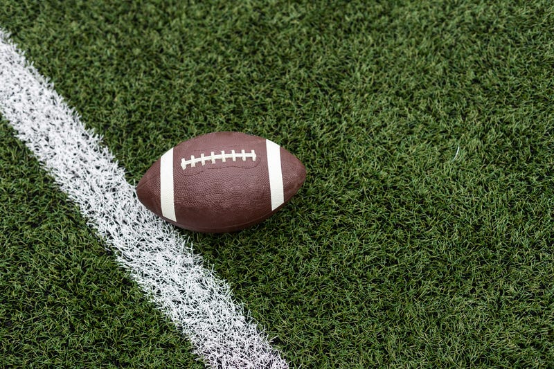 Football by a yard marker on a football field.