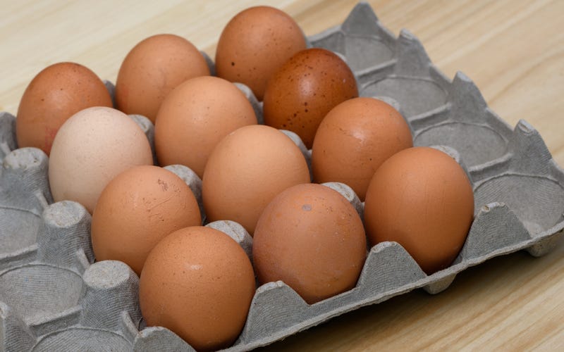 A dozen chicken eggs in a paper package lie on the table
