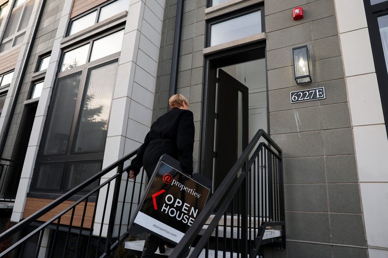 Joanna Olszynska, a Compass real estate broker, brings in a sign at the end of an open house for a single-family row house in Chicago's Woodlawn neighborhood on Jan. 21, 2024.