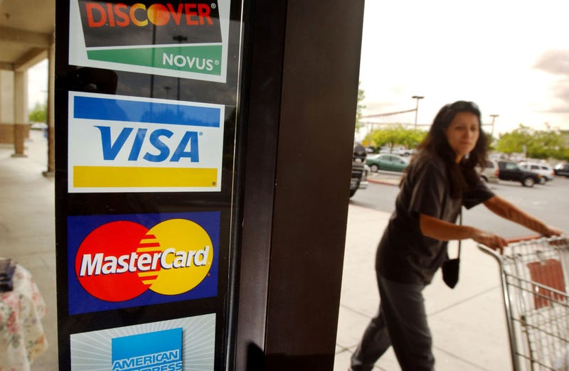 A shopper passes a shop door advertising acceptance of purchases with Master Card, Visa, and other credit cards April 29, 2003 in Bakersfield, California.