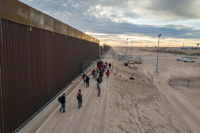 Seen from an aerial view, immigrants walk along the U.S.-Mexico border wall after crossing the Rio Grande into El Paso, Texas on Feb. 1, 2024.
