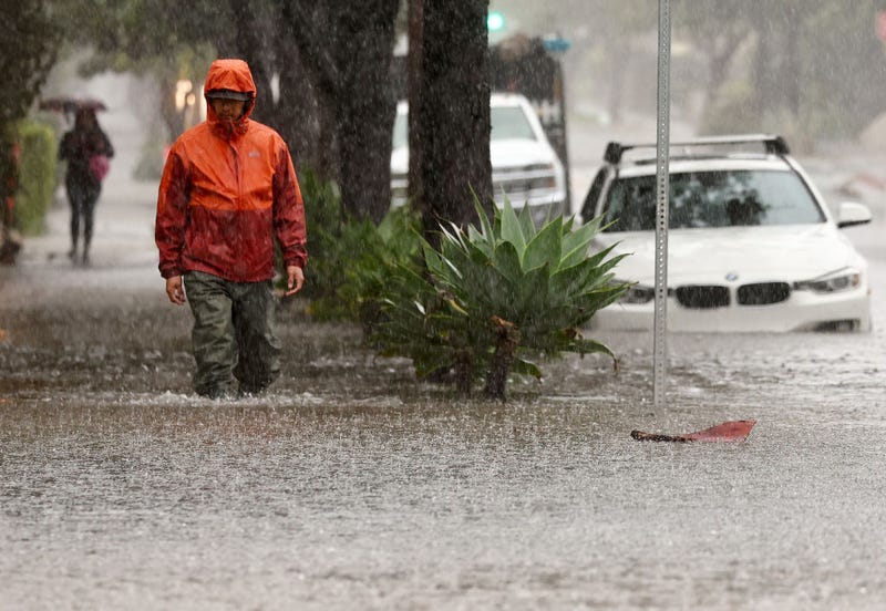 A person walks along a flooded street as a powerful long-duration atmospheric river storm, the second in less than a week, impacts California on February 4, 2024 in Santa Barbara, California. The storm is delivering potential for widespread flooding, landslides and power outages while dropping heavy rain and snow across the region.