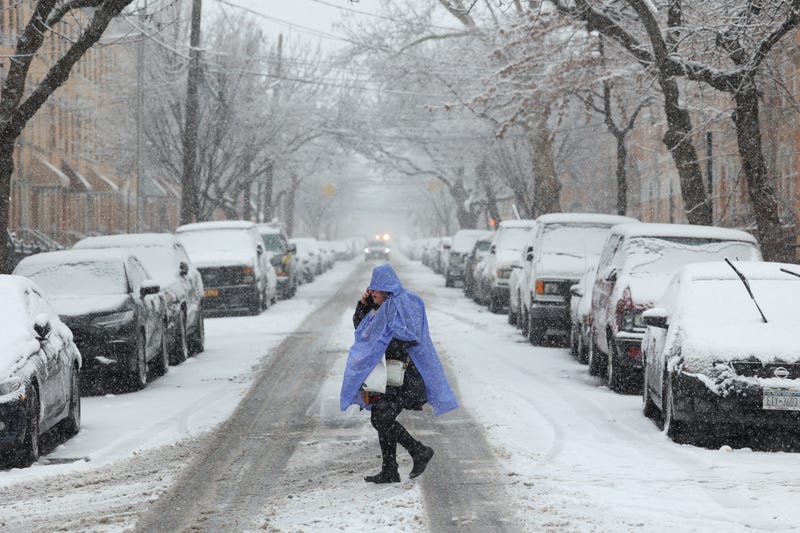 A person crosses the street as snow falls in Brooklyn on February 13, 2024