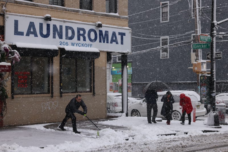 A man clears snow off a sidewalk in Brooklyn on February 13, 2024