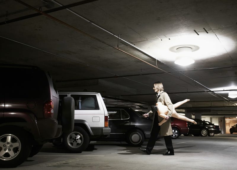 Young businessman carrying blow-up doll in parking garage
