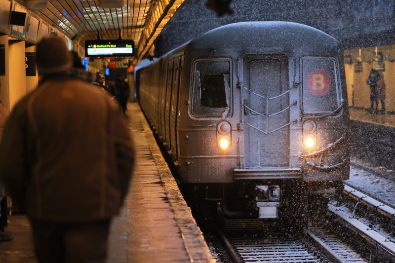 People walk at the Church Avenue subway station in Flatbush as a train arrives amid a winter storm on February 13, 2024