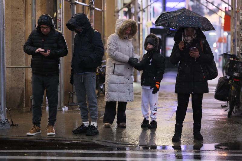 People wait to cross the street in Times Square amid a winter storm on the morning of February 13, 2024
