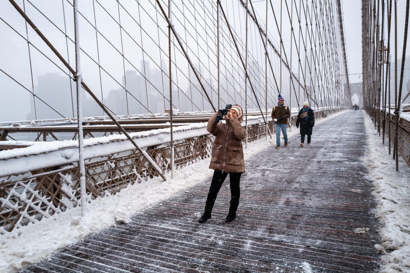 People walk across the Brooklyn Bridge in the blowing snow on Feb. 13, 2024