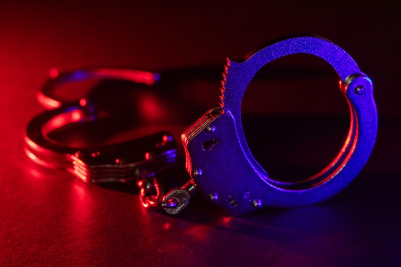 Silhouette of handcuffs with the flashing red and blue police lights