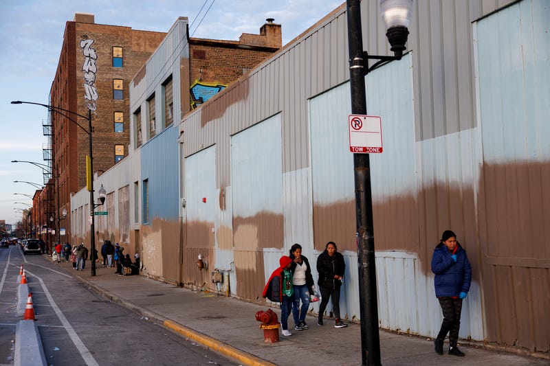 Migrants walk outside a shelter where they're staying near the 2300 block of South Halsted Street on Tuesday Dec. 19, 2023, in Chicago.